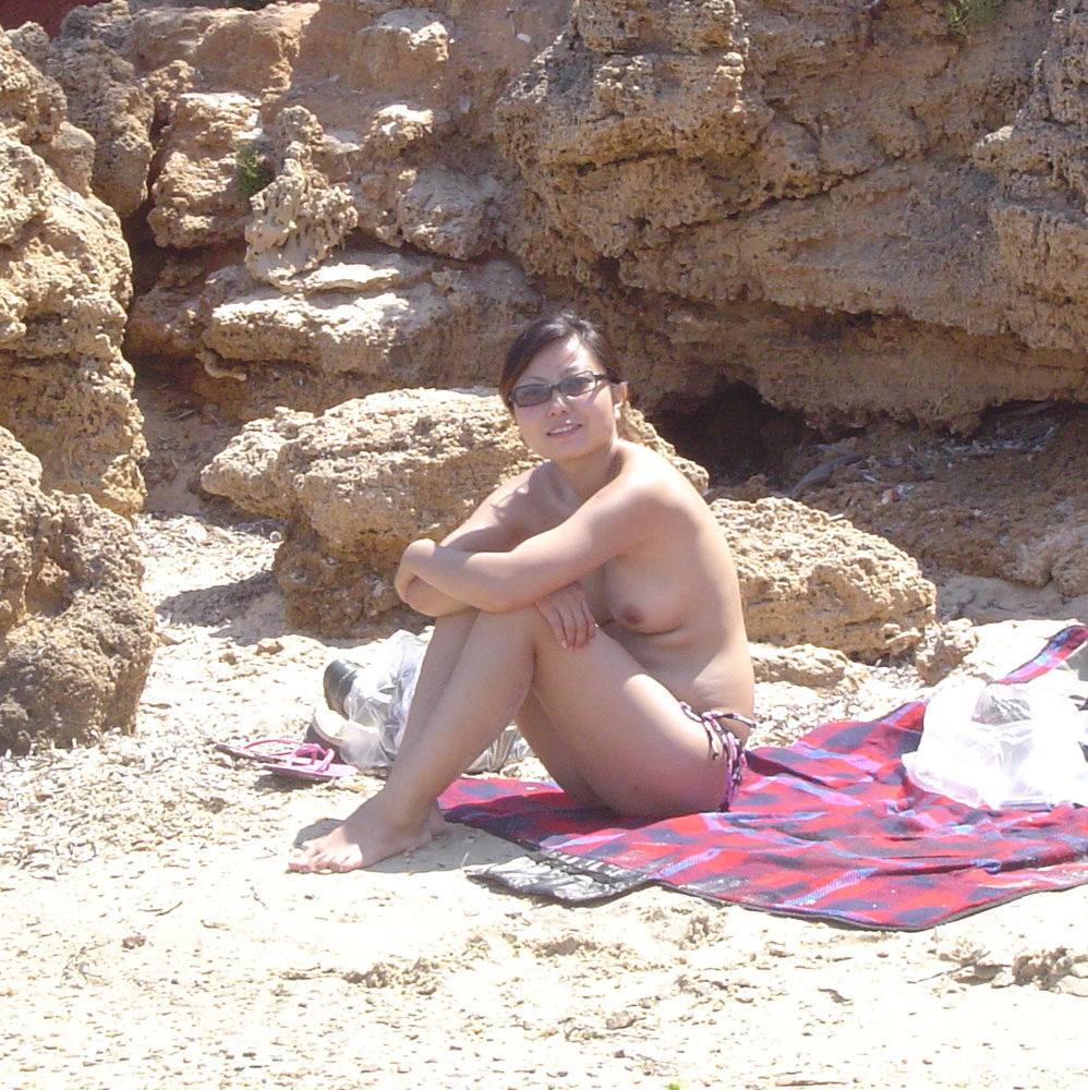 Asian wife sunbathing on public beach picture
